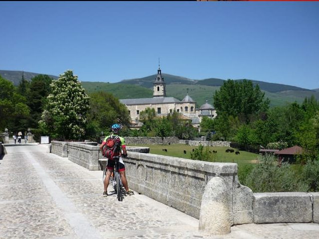 Hombre en bicicleta detenido frente a un monumento, disfrutando de la vista.