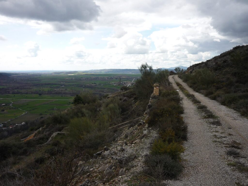 Vista de un camino de tierra elevado que serpentea por el monte, ideal para rutas.