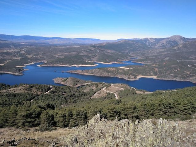 Perspectiva elevada de un lago rodeado de montañas y paisajes naturales.