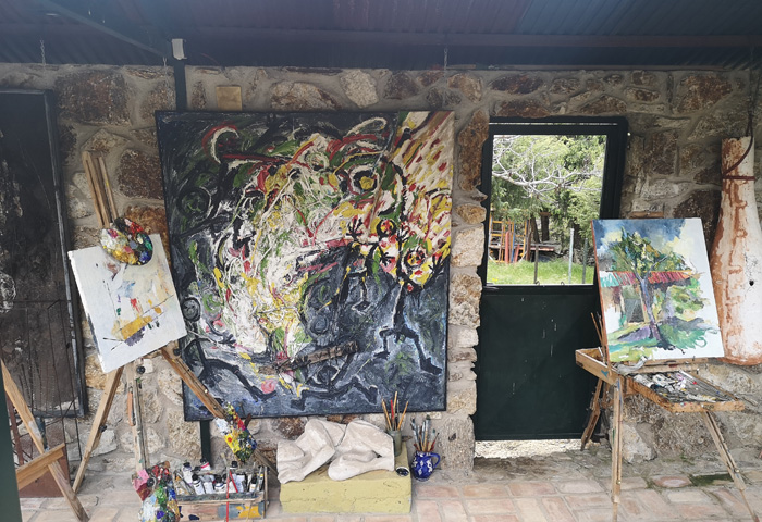 Estudio de arte con varias pinturas y materiales artísticos, destacando obras contemporáneas.