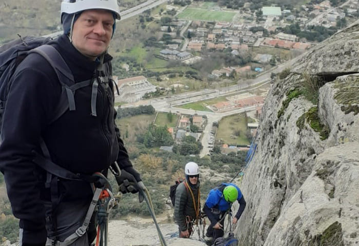 Escalador ascendiendo una roca en un paisaje montañoso.